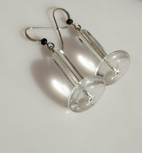 Load image into Gallery viewer, Clear acrylic disc and crystal Quartz tubes with silver fishhook wires and small black Onyx beads, displayed on a white surface with gray stones in the background.