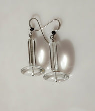 Load image into Gallery viewer, Clear acrylic disc and crystal Quartz tubes with silver fishhook wires and small black Onyx beads, displayed on a white surface with gray stones in the background.