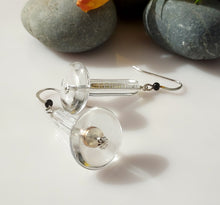 Load image into Gallery viewer, Clear acrylic disc and crystal Quartz tubes with silver fishhook wires and small black Onyx beads, displayed on a white surface with gray stones in the background.