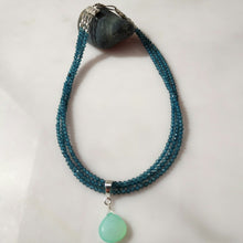 Load image into Gallery viewer, A beaded necklace with multiple strands of blue topaz beads and a teardrop-shaped Chrysopase green gemstone pendant, with Sterling silver findings.displayed on a light surface.