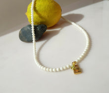 Load image into Gallery viewer, A beaded necklace made of small white jade beads with a 14 karat gold-filled padlock pendant featuring a heart and and a small green gemstone charm, and a lobster claw clasp.