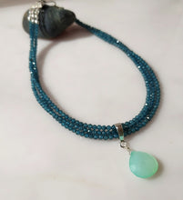 Load image into Gallery viewer, A beaded necklace with multiple strands of blue topaz beads and a teardrop-shaped Chrysopase green gemstone pendant, with Sterling silver findings.displayed on a light surface.
