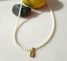 Load image into Gallery viewer, A beaded necklace made of small white jade beads with a 14 karat gold-filled padlock pendant featuring a heart and and a small green gemstone charm, and a lobster claw clasp.
